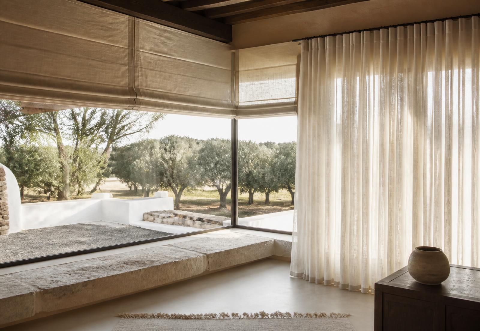Janela panorâmica sobre um olival alentejano com estores romanos e cortinado translúcido em linho